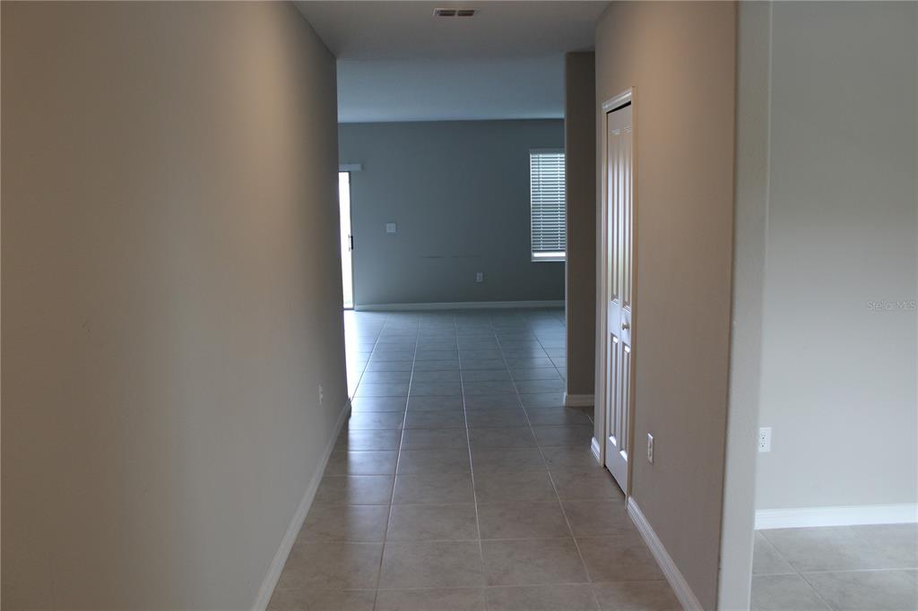 A tiled hallway leads into an open living area with a sliding glass door — 12916 WILDFLOWER MEADOW DRIVE, RIVERVIEW, FL