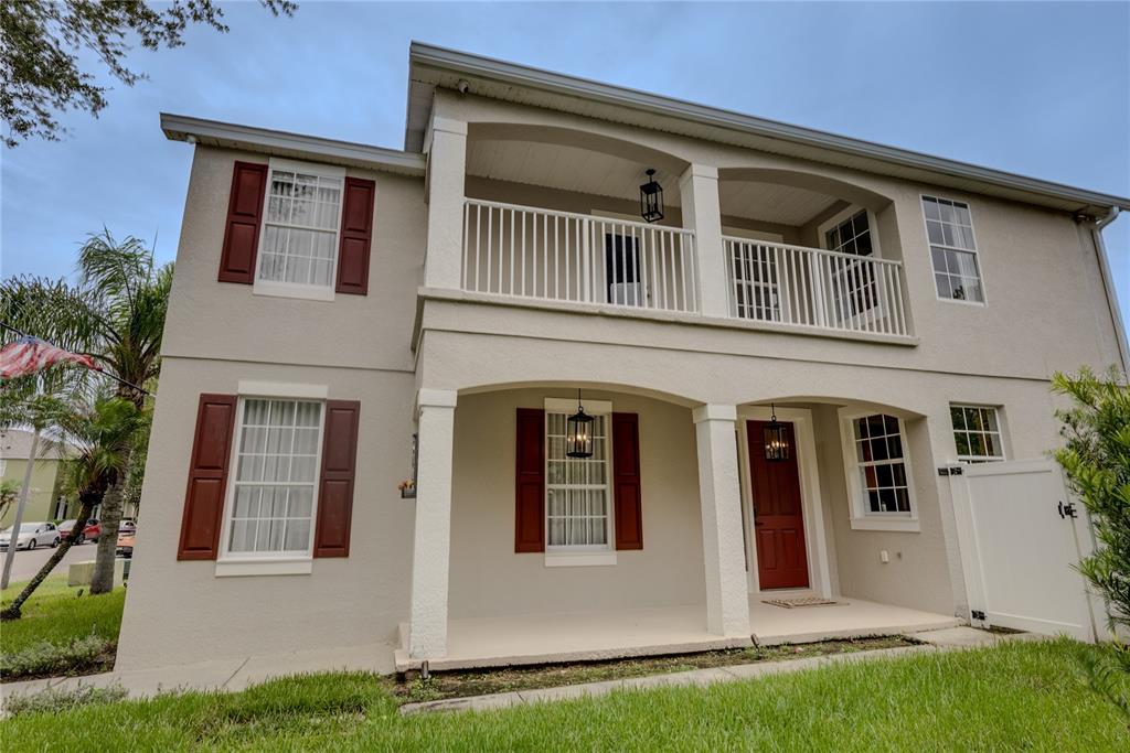 A two-story house with a beige stucco exterior, red shutters, and a covered front porch — 644 AUTUMN OAKS LOOP, WINTER GARDEN, FL