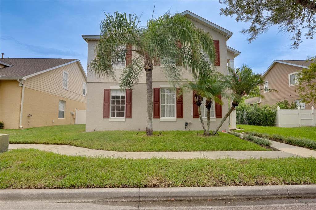 A two-story house with beige stucco siding, red shutters, and palm trees in the front yard — 644 AUTUMN OAKS LOOP, WINTER GARDEN, FL