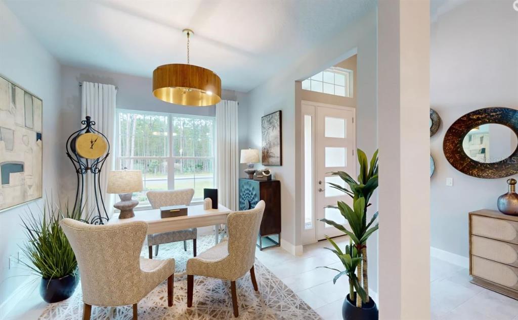 A home office features a desk, chairs, a pendant light, and a view of trees — 52 BRIGHTON LANE, ORMOND BEACH, FL
