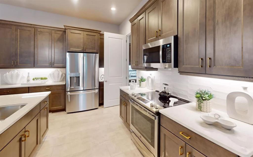 A kitchen features dark wood cabinets, stainless steel appliances, and white countertops — 52 BRIGHTON LANE, ORMOND BEACH, FL
