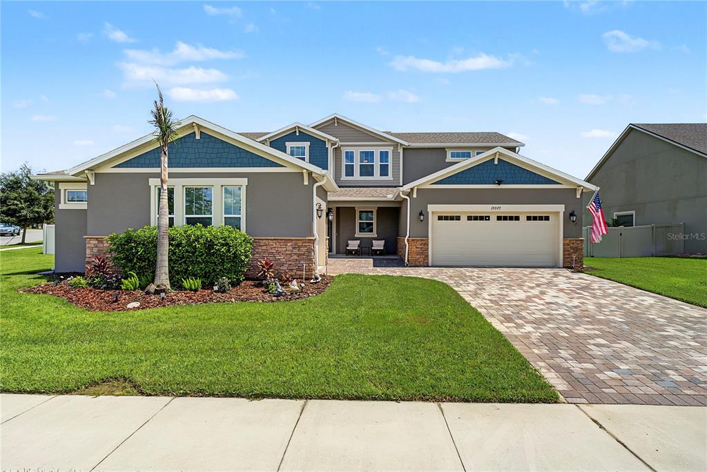 A two-story suburban house features a paved driveway, a front lawn, and blue siding accents — 17077 WINGSPREAD LOOP, WINTER GARDEN, FL