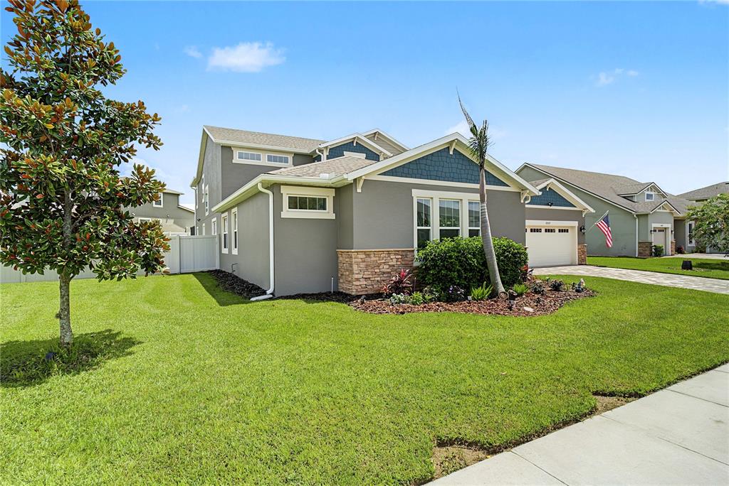 A gray two-story house with stone accents, a palm tree, and a green lawn — 17077 WINGSPREAD LOOP, WINTER GARDEN, FL