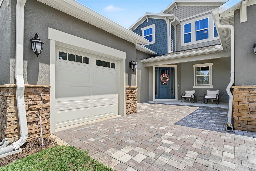 A two-story house exterior features a stone-accented garage, a paved driveway, and a blue front door — 17077 WINGSPREAD LOOP, WINTER GARDEN, FL