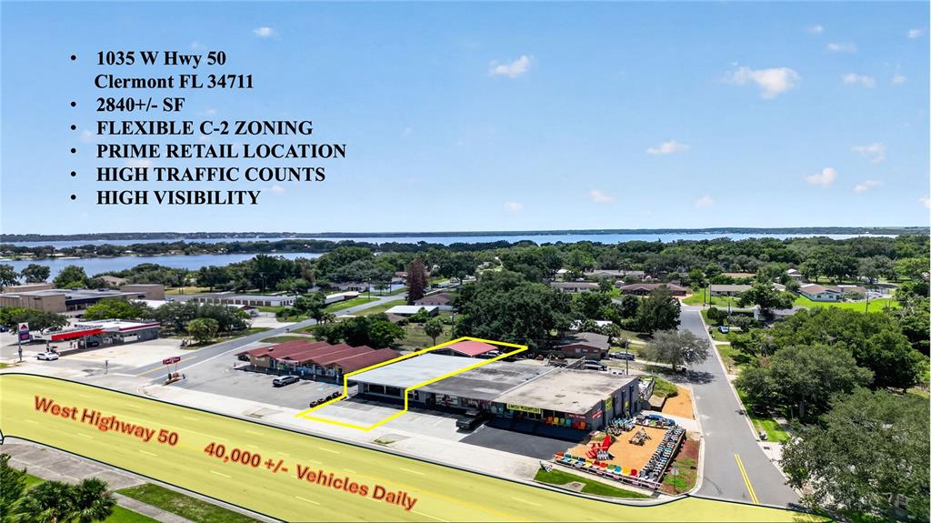 An aerial view shows a commercial strip mall building highlighted in yellow along a highway — 1035 W HIGHWAY 50 HIGHWAY, CLERMONT, FL