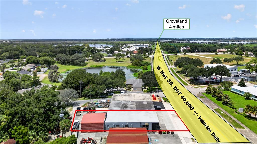 This aerial view shows a commercial building with a red-roofed section next to a highway — 1035 W HIGHWAY 50 HIGHWAY, CLERMONT, FL