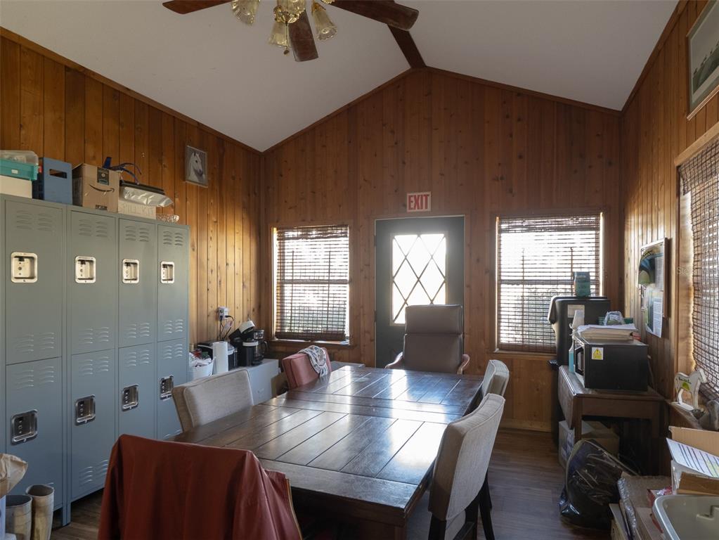 A room with wood-paneled walls, a large dining table, gray lockers, and a ceiling fan — 11122 W HIGHWAY 326, OCALA, FL