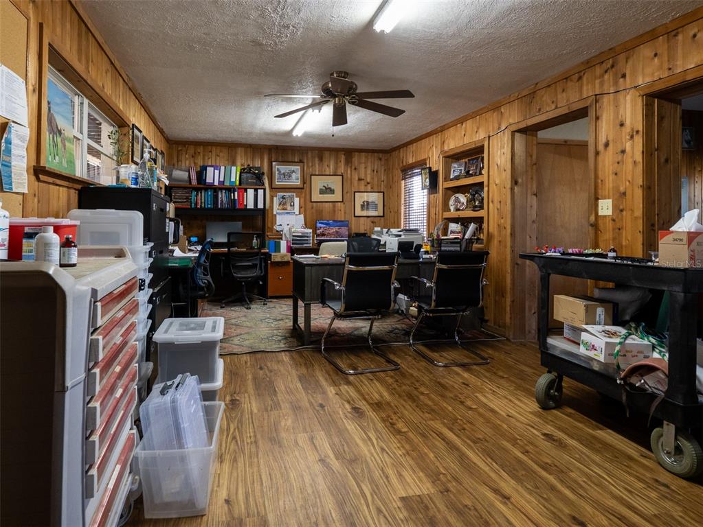 A home office features wood-paneled walls, wood-look flooring, a ceiling fan, and two desks — 11122 W HIGHWAY 326, OCALA, FL
