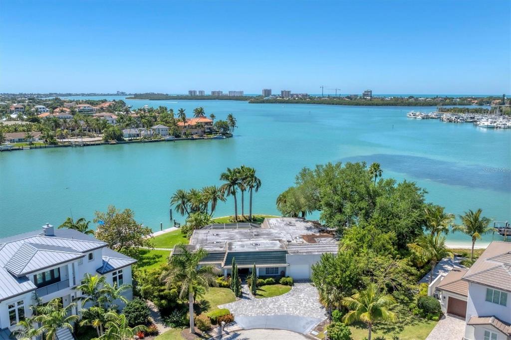 An aerial view of a waterfront house with a paved driveway and palm trees — 102 SEAGULL LANE, SARASOTA, FL