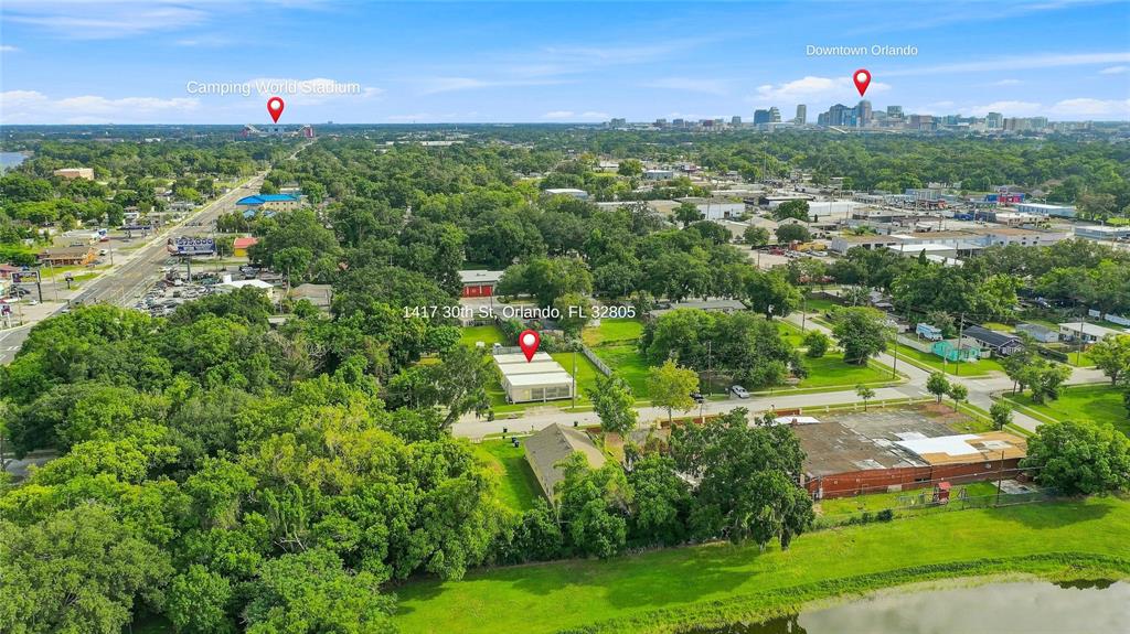 This aerial view shows a property with multiple buildings, surrounding trees, and a nearby lake — 1417 30TH ST, ORLANDO, FL