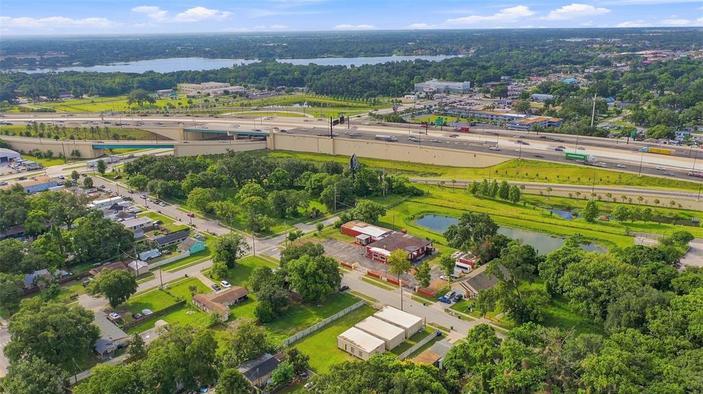 An aerial view shows a commercial building, residential houses, and a highway overpass near water — 1417 30TH ST, ORLANDO, FL