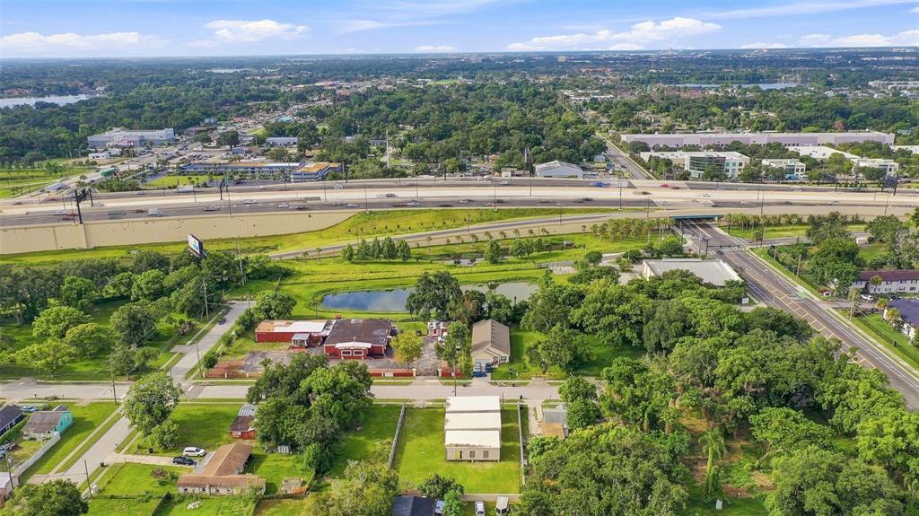 An aerial view shows a commercial building with a pond, parking lot, and nearby highway — 1417 30TH ST, ORLANDO, FL