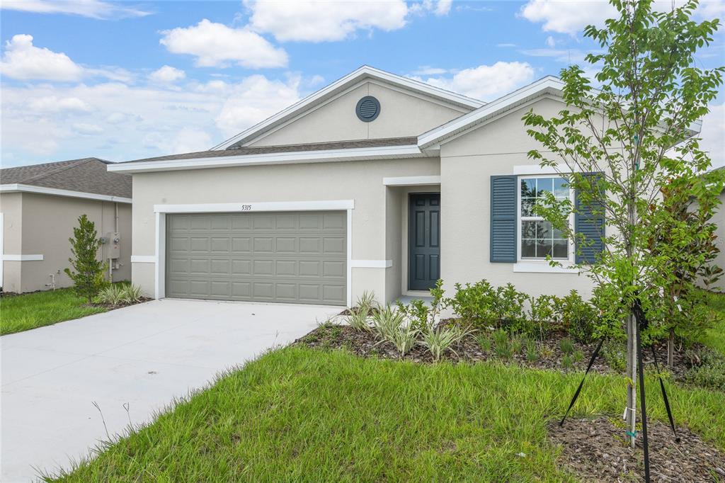 A single-story house with a beige stucco exterior, a two-car garage, and blue shutters — 5315 MICKEY AVENUE, WINTER HAVEN, FL