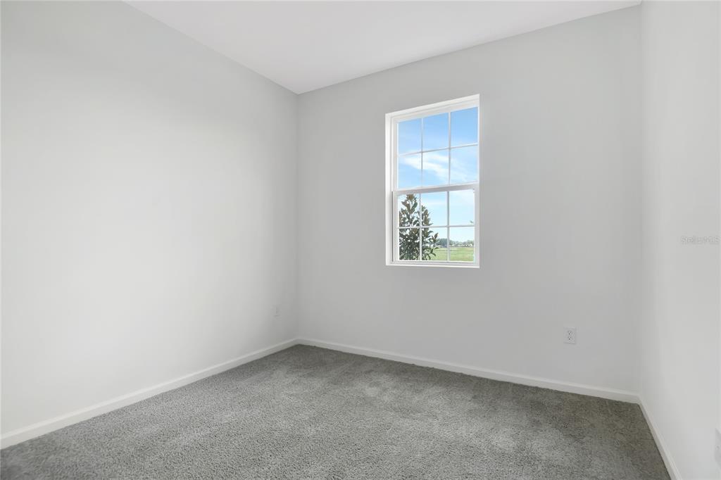 A small, empty bedroom features light gray walls, gray carpeting, and a single window — 5315 MICKEY AVENUE, WINTER HAVEN, FL