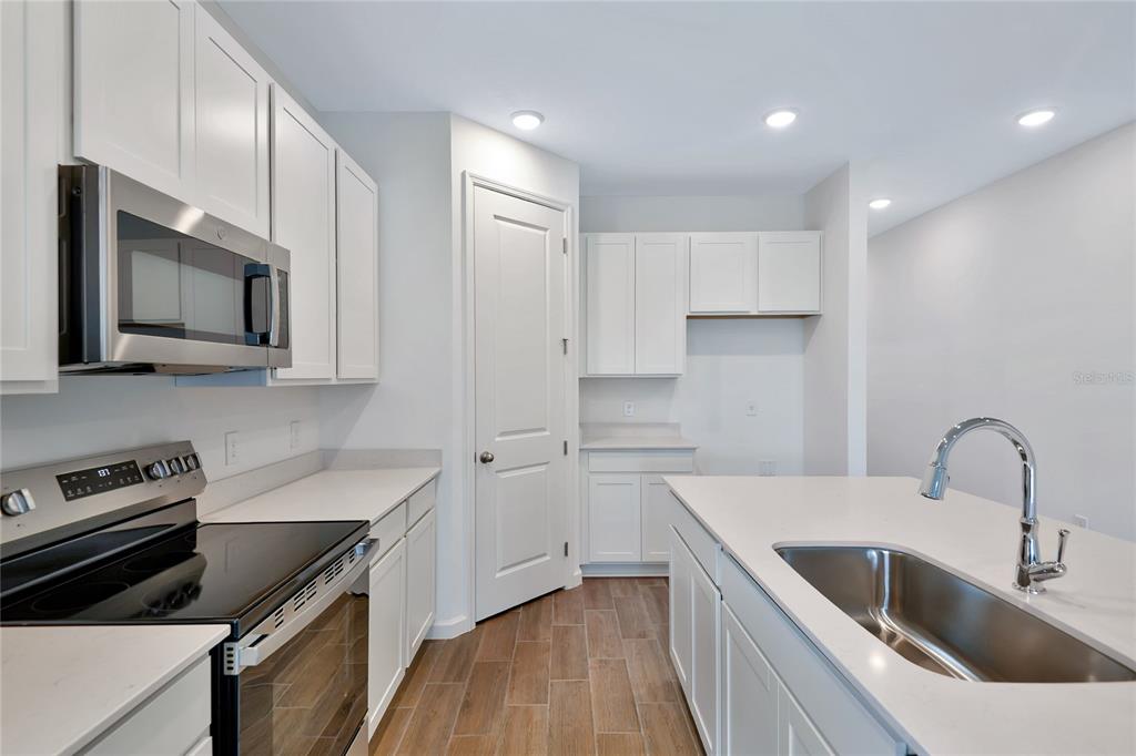 A modern kitchen features white cabinets, stainless steel appliances, a center island, and wood-look flooring — 5315 MICKEY AVENUE, WINTER HAVEN, FL