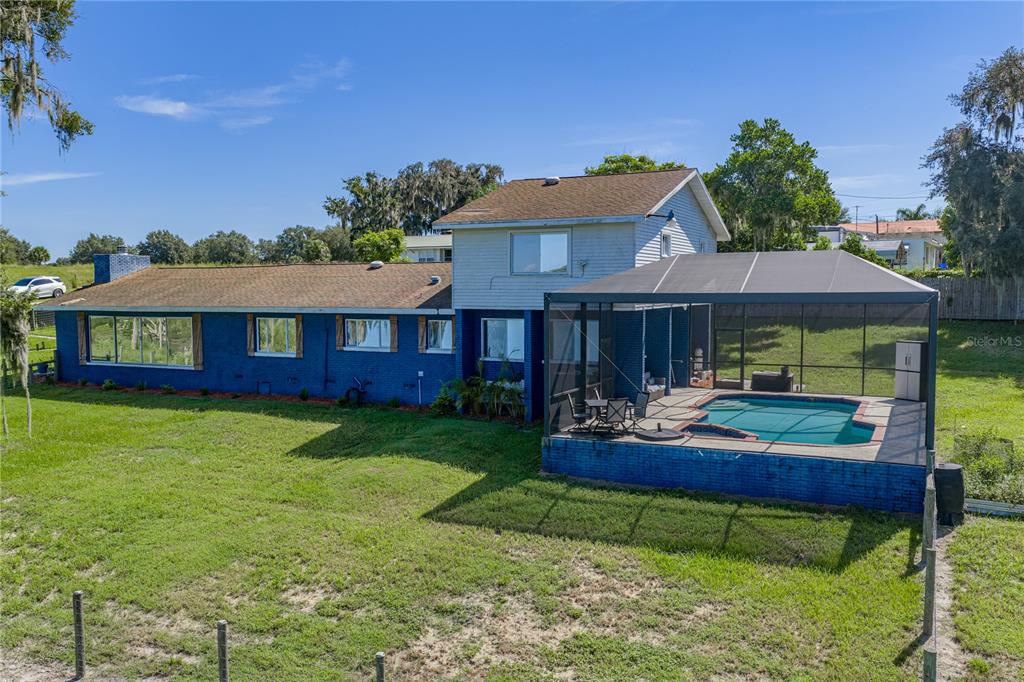 A two-story blue brick house features a screened-in pool and a large grassy backyard — 2120 HURLEY DRIVE, BARTOW, FL