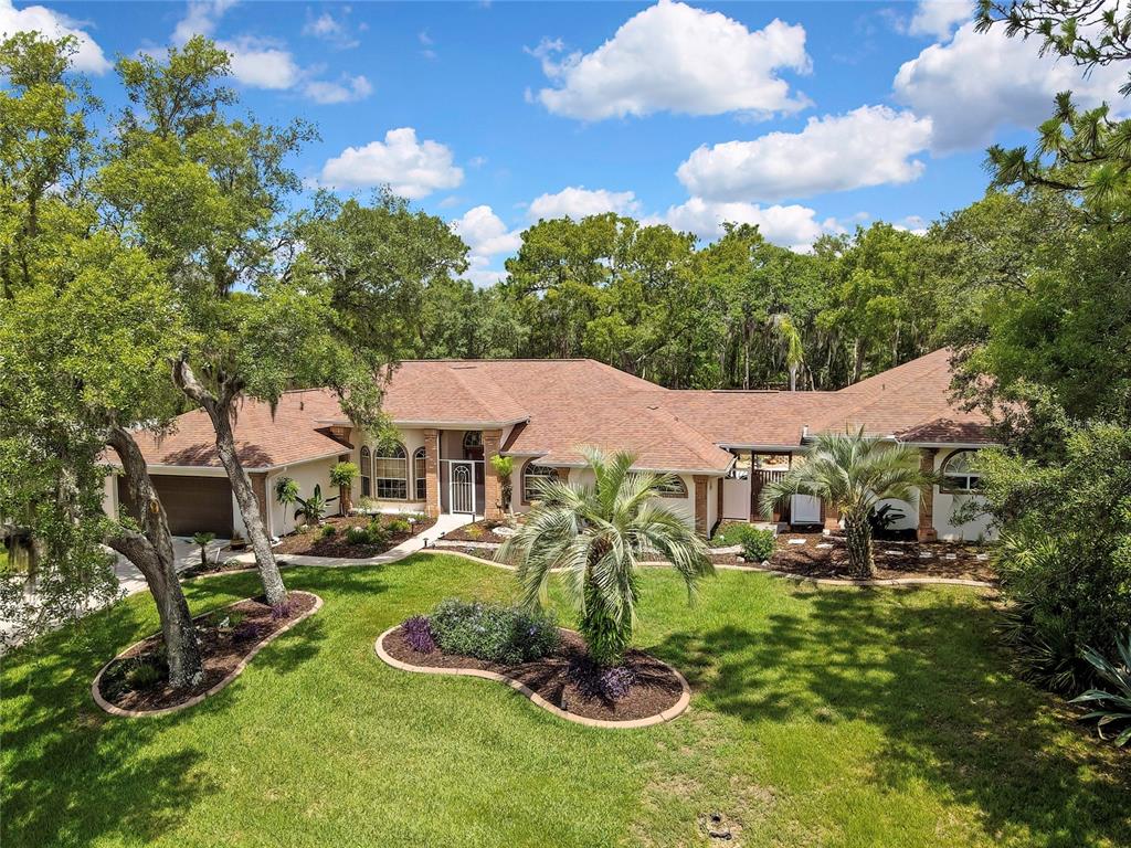 A single-story house with a brown roof, brick accents, and a large front lawn — 5701 W CHIVE LOOP, HOMOSASSA, FL