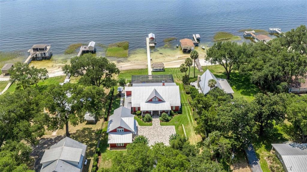 An aerial view shows a red house with a metal roof near a lakefront dock — 11940 SE 128TH PLACE ROAD, OCKLAWAHA, FL