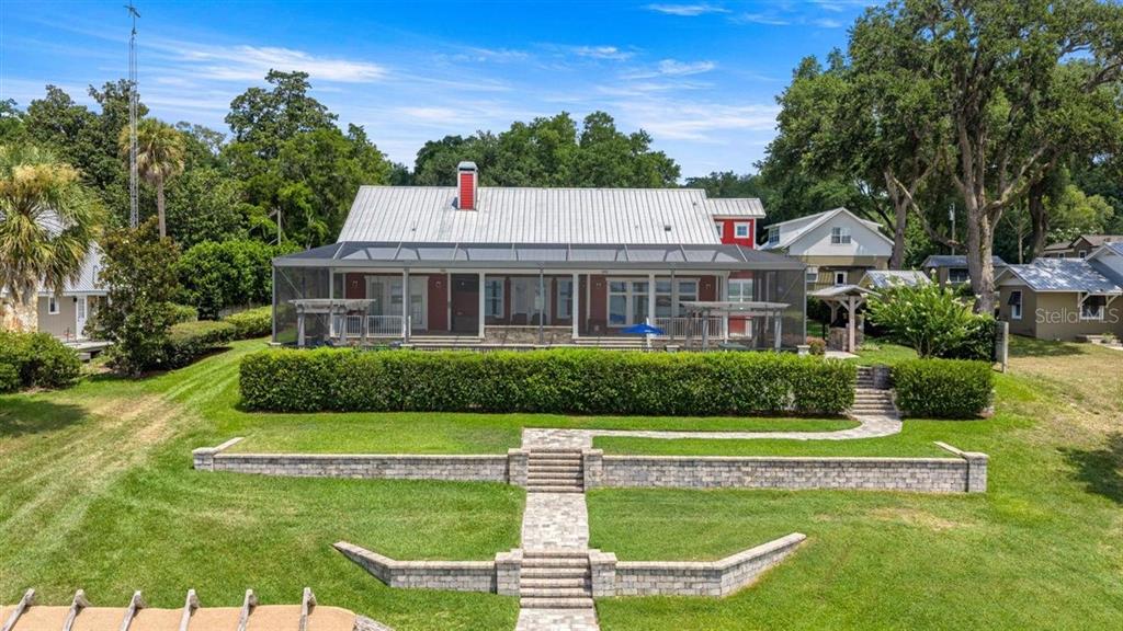 An aerial view shows a house with a metal roof and a large screened-in porch — 11940 SE 128TH PLACE ROAD, OCKLAWAHA, FL