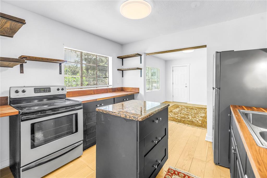 A kitchen features black cabinets, a granite-topped island, wood countertops, and stainless steel appliances — 2000 27TH AVENUE N, ST PETERSBURG, FL