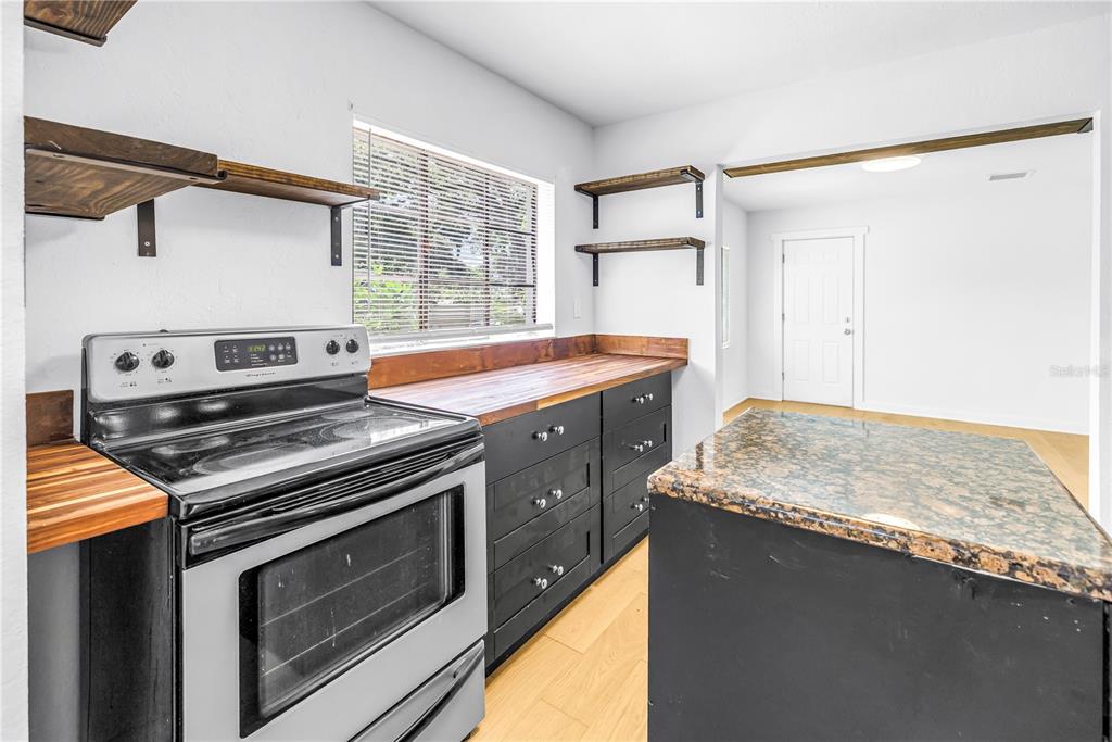 A kitchen features black cabinets, a butcher block countertop, a stainless steel stove, and an island — 2000 27TH AVENUE N, ST PETERSBURG, FL