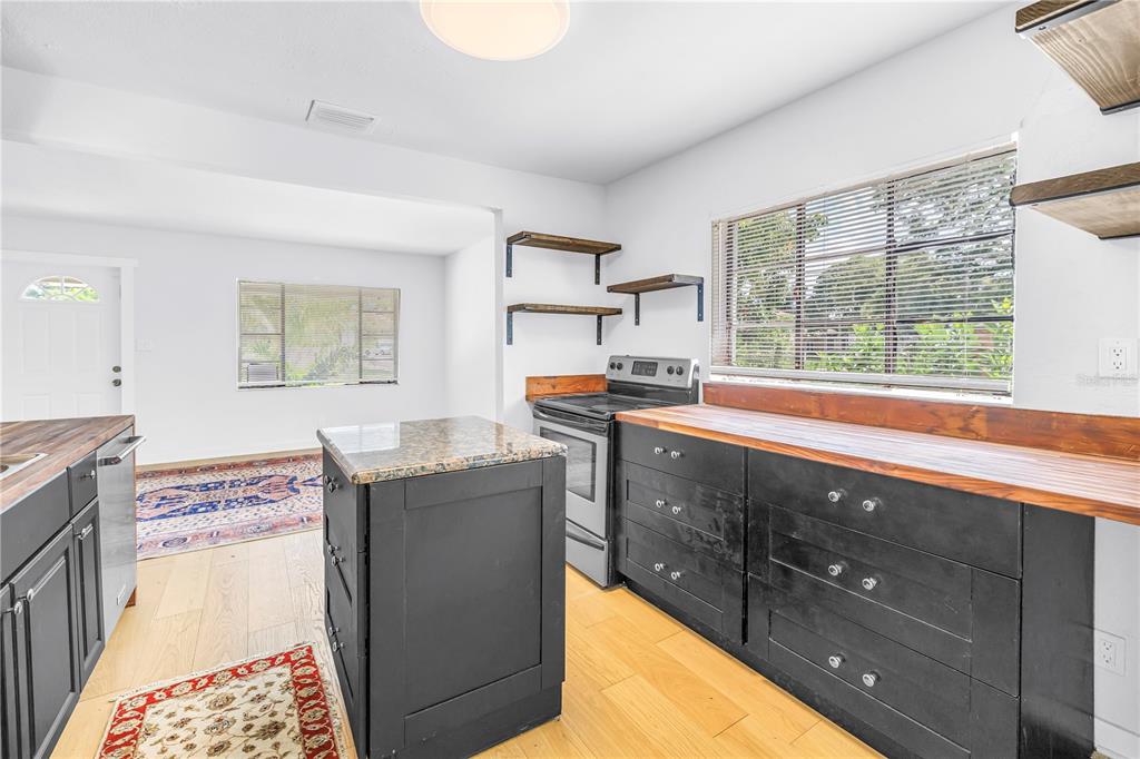 A kitchen features black cabinets, a granite-topped island, wood countertops, and light wood flooring — 2000 27TH AVENUE N, ST PETERSBURG, FL