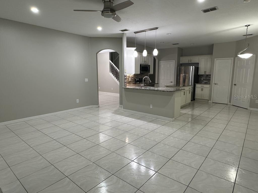 An open-concept kitchen with white cabinets, granite countertops, and tile flooring — 4743 CHALFONT DRIVE, ORLANDO, FL