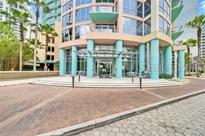 The exterior entrance of a multi-story building features turquoise columns and a glass canopy — 322 E CENTRAL BLVD UNIT 1807, ORLANDO, FL