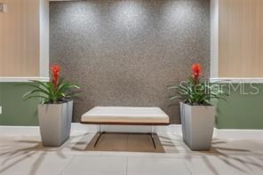 A white bench sits between two potted plants against a textured gray accent wall — 322 E CENTRAL BLVD UNIT 1807, ORLANDO, FL