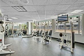 A fitness center with various exercise machines, large windows, and a drop ceiling — 322 E CENTRAL BLVD UNIT 1807, ORLANDO, FL