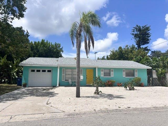 A single-story teal house with a white garage door, yellow front door, and palm tree — 8218 43RD AVENUE W, BRADENTON, FL