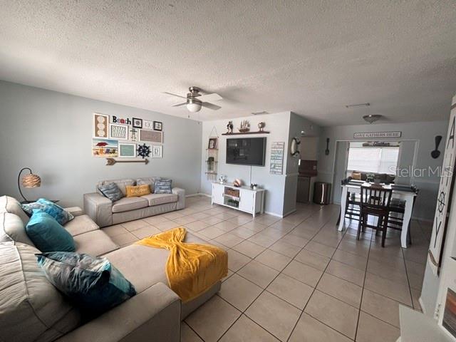 A living room with tile floors, a sectional sofa, a television, and a dining area — 8218 43RD AVENUE W, BRADENTON, FL