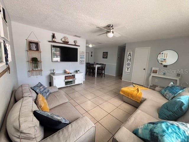 A living room with light-colored tile floors, a sectional sofa, and a wall-mounted television — 8218 43RD AVENUE W, BRADENTON, FL