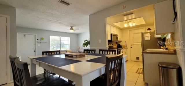 A dining area with a white table and chairs opens into a kitchen with cabinets — 8218 43RD AVENUE W, BRADENTON, FL