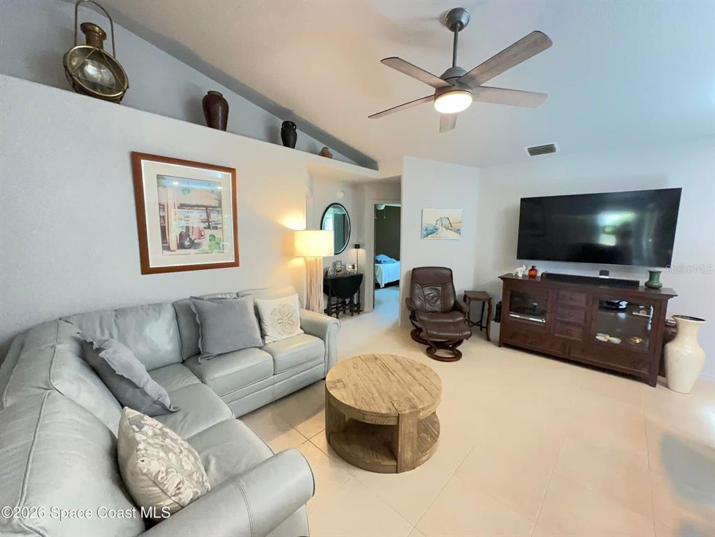 A living room features a light gray sectional sofa, a wooden coffee table, and a television — 130 COUNTRY WOODS PLACE, MERRITT ISLAND, FL