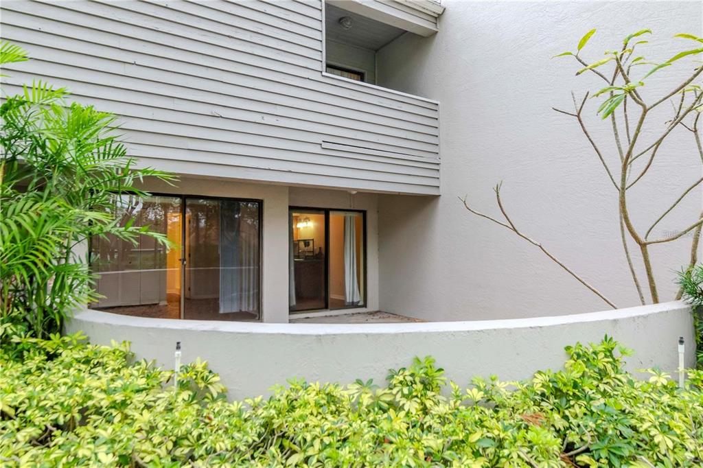 A ground-level patio with sliding glass doors sits beneath a second-story balcony and siding — 8737 BARDMOOR PLACE UNIT 101, SEMINOLE, FL