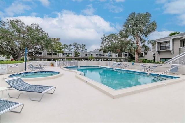 A swimming pool and hot tub are surrounded by lounge chairs and apartment buildings — 8737 BARDMOOR PLACE UNIT 101, SEMINOLE, FL