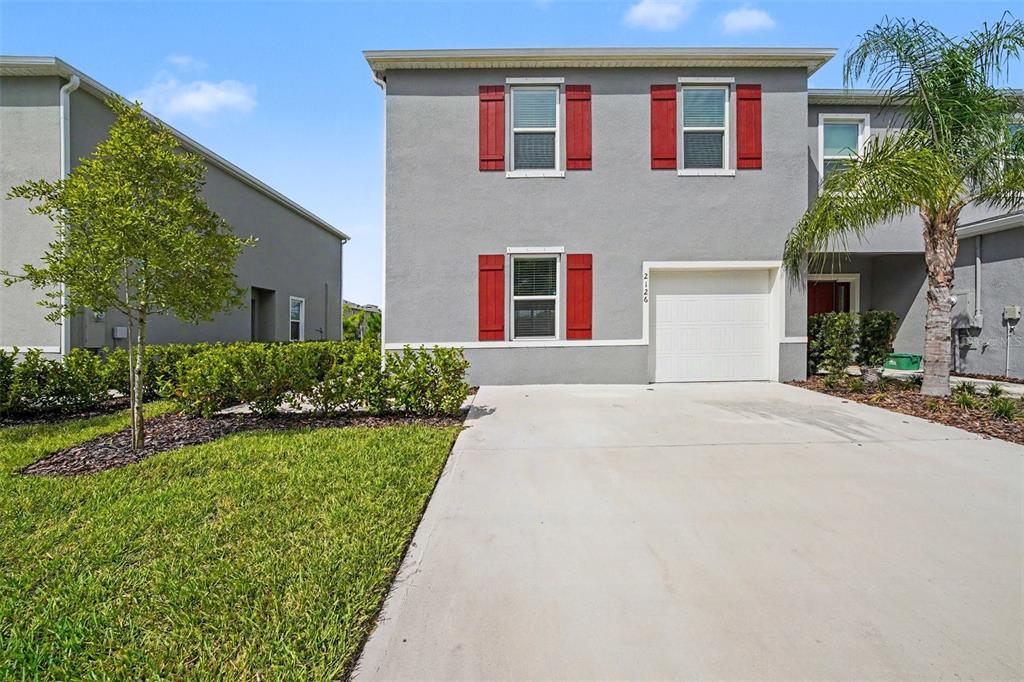 A two-story gray house with red shutters and a concrete driveway under a blue sky — 2126 GENTLE RAIN DRIVE, EDGEWATER, FL