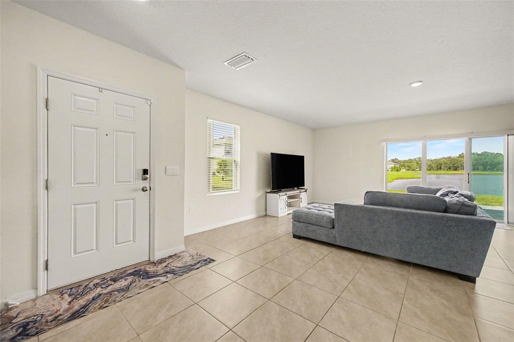 A living room features light tile floors, a white front door, and sliding glass patio doors — 2126 GENTLE RAIN DRIVE, EDGEWATER, FL