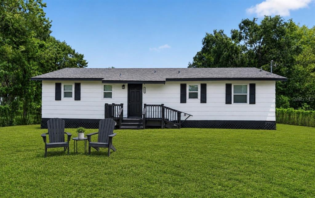 A white, single-story house with black shutters, a black front door, and a wooden deck — 1911 WATER STREET, SANFORD, FL