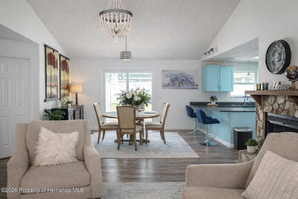 A living room features a stone fireplace, light wood-look flooring, and a beige sofa — 15499 ARVIN DRIVE, BROOKSVILLE, FL
