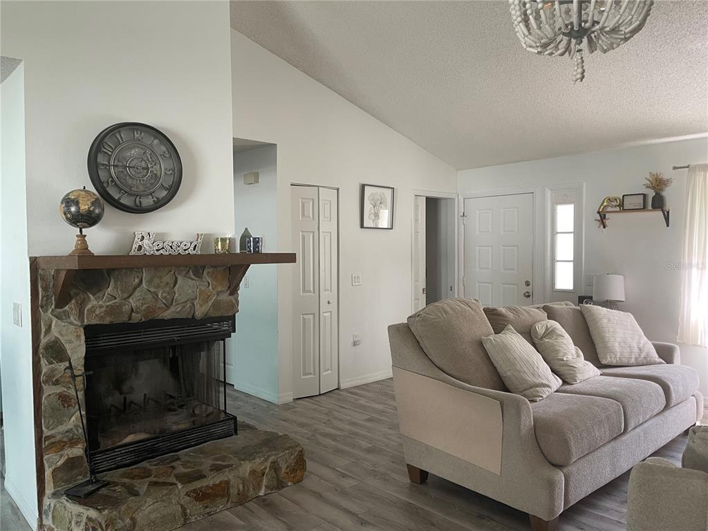 A living room with a stone fireplace and a view into a turquoise kitchen — 15499 ARVIN DRIVE, BROOKSVILLE, FL