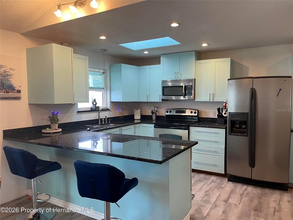 A bedroom features a stone fireplace, dark wood furniture, and a purple bedspread — 15499 ARVIN DRIVE, BROOKSVILLE, FL