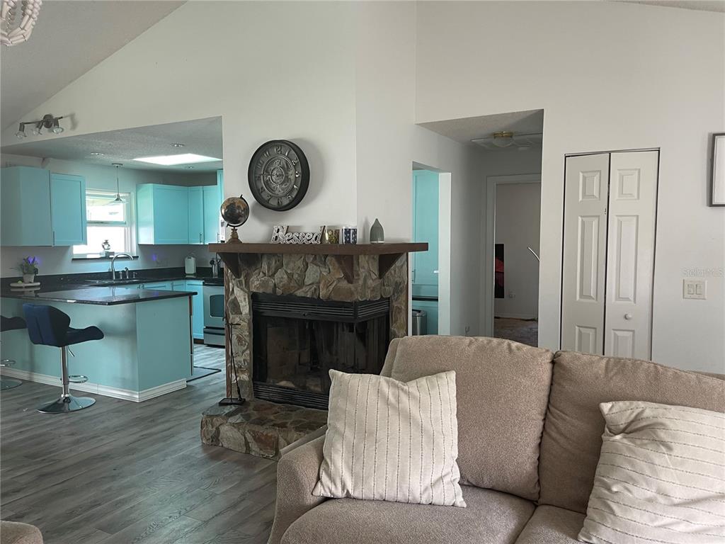 A bedroom features a stone fireplace, a dark wood dresser with a mirror, and a bed — 15499 ARVIN DRIVE, BROOKSVILLE, FL