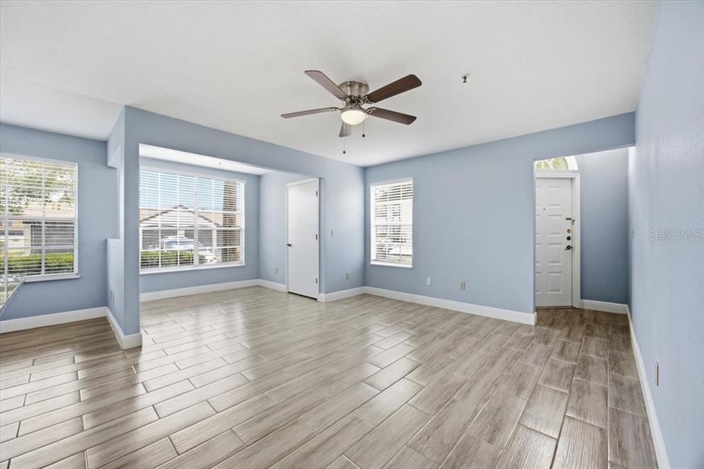 A bright living room features light blue walls, wood-look tile flooring, and a ceiling fan — 1612 COLUMBIA ARMS CIRCLE UNIT 137, KISSIMMEE, FL