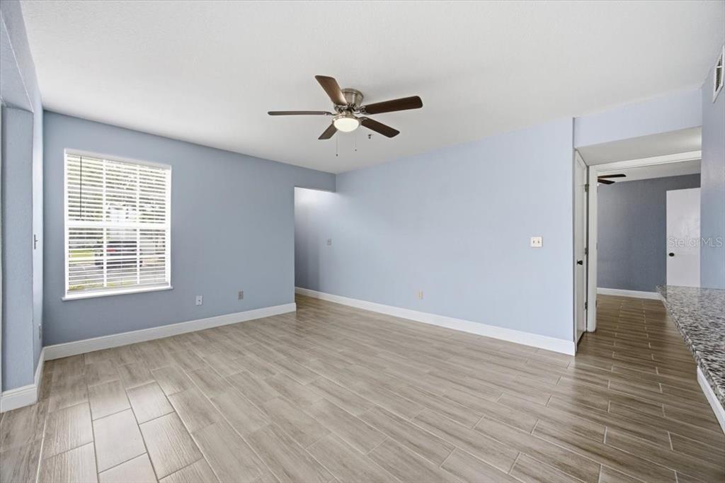 A living room features light blue walls, wood-look tile flooring, and a ceiling fan — 1612 COLUMBIA ARMS CIRCLE UNIT 137, KISSIMMEE, FL