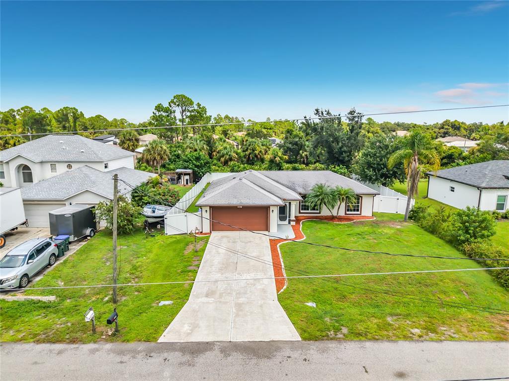 An aerial view shows a single-story house with a brown garage door and concrete driveway — 2198 ALLIANCE AVENUE, NORTH PORT, FL