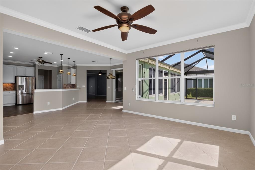 An open-concept living area with tile floors, a ceiling fan, and a view of a lanai — 9439 SW 71ST LOOP, OCALA, FL