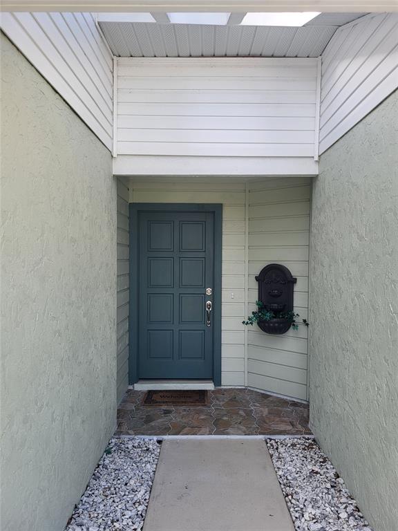 A blue front door is set within a recessed entryway featuring stone flooring and gravel — 482 PENDLETON PLACE, VENICE, FL