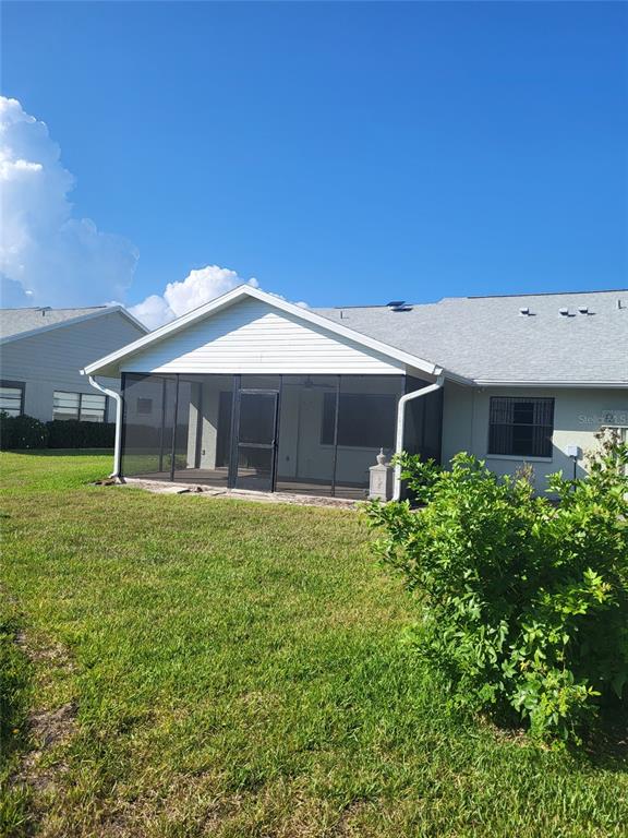 A rear view of a house featuring a screened-in porch and a grassy backyard — 482 PENDLETON PLACE, VENICE, FL